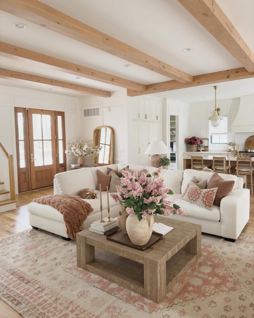 White sectional sofa under exposed ceiling beams with farmhouse kitchen