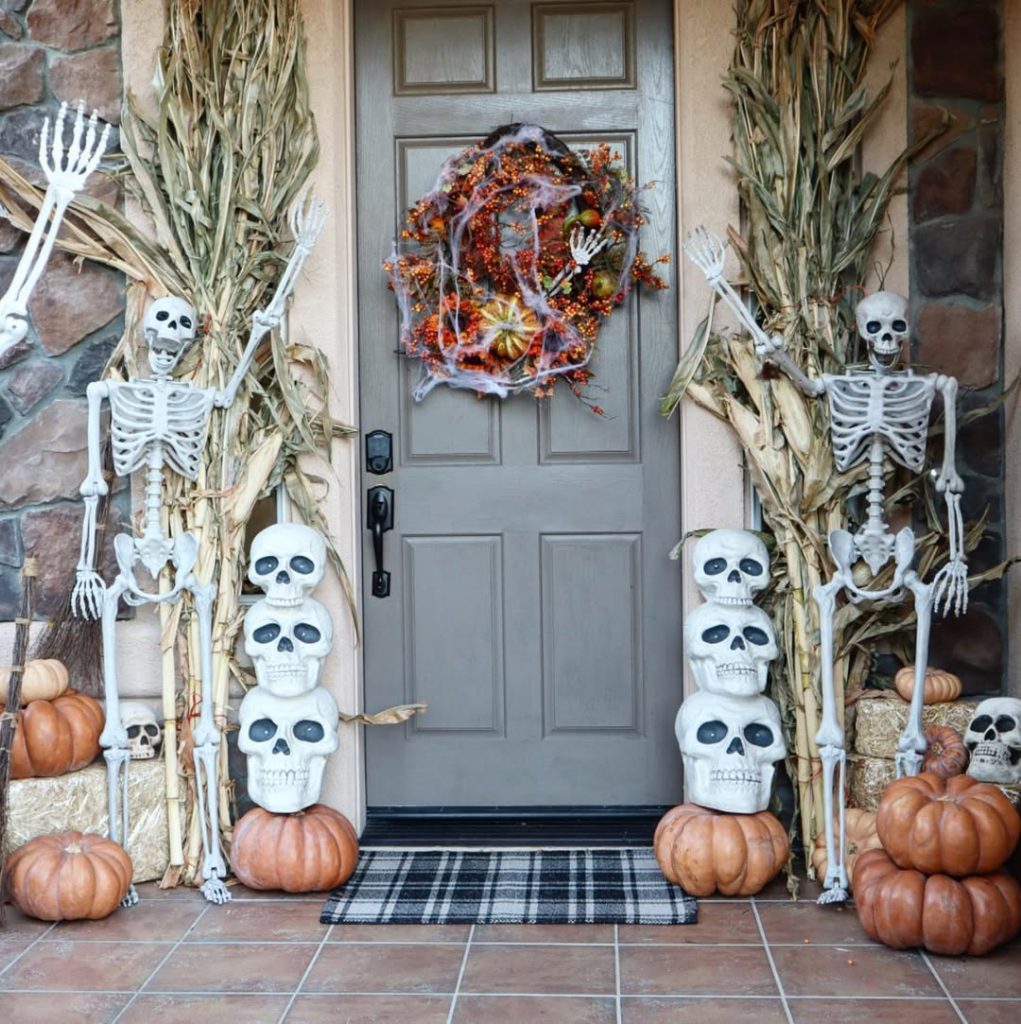 Front door decorated with skeleton figures and autumn elements