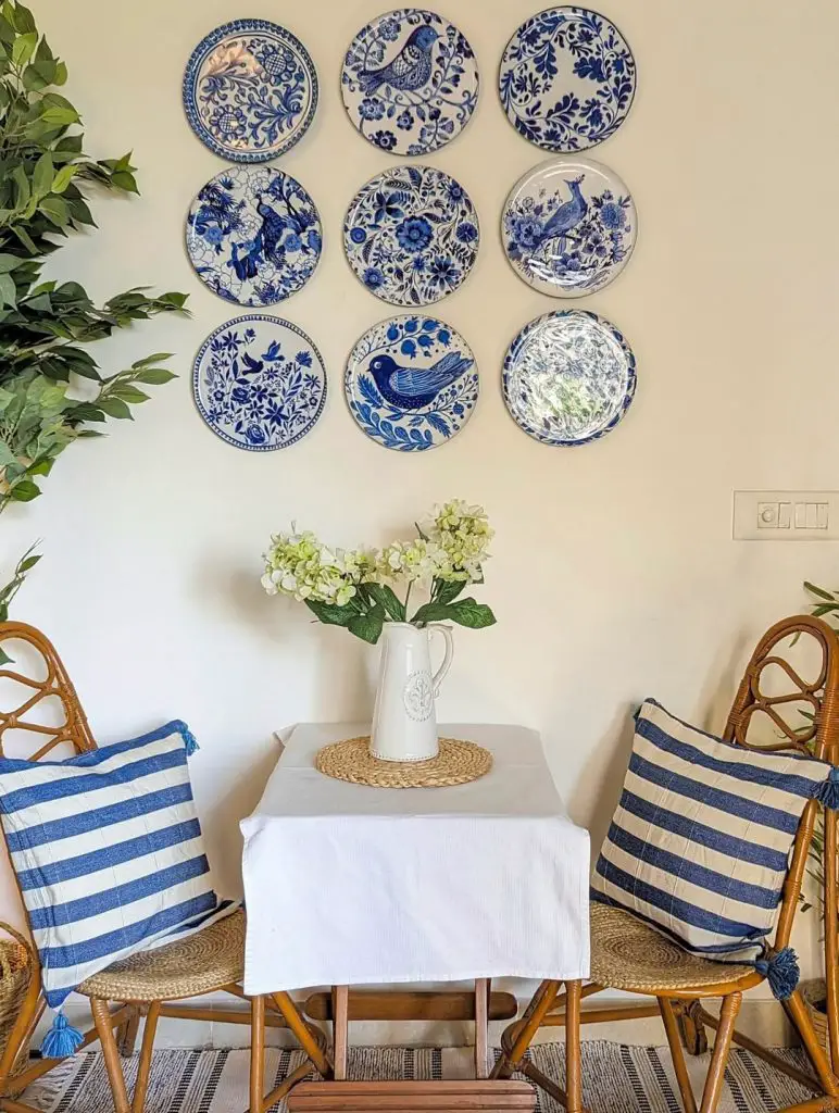 Blue and white plate wall display with striped dining chairs