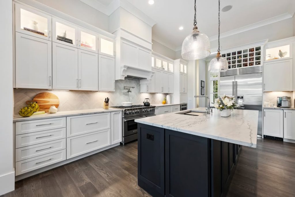 Traditional kitchen with navy island, white cabinets, globe pendant lights, marble countertops