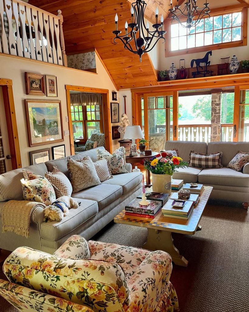 Traditional living room with wood beams, floral furniture, striped sofas, and raised balcony area