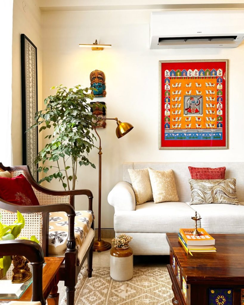 White sectional sofa with traditional Indian artwork and brass lighting accents