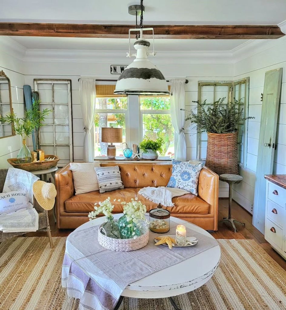 Farmhouse living room with cognac leather sofa, white walls, jute rug, and industrial pendant lighting