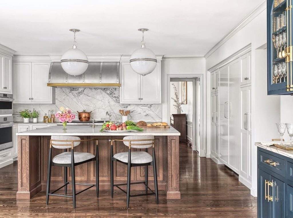 Elegant kitchen with bowl pendant lights, wood island, marble backsplash, brass hardware