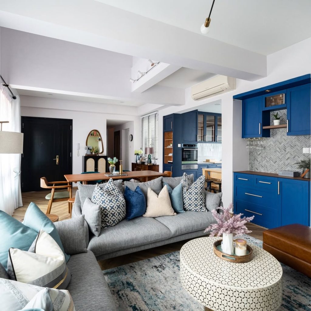  Open living space with bold blue kitchen and gray seating