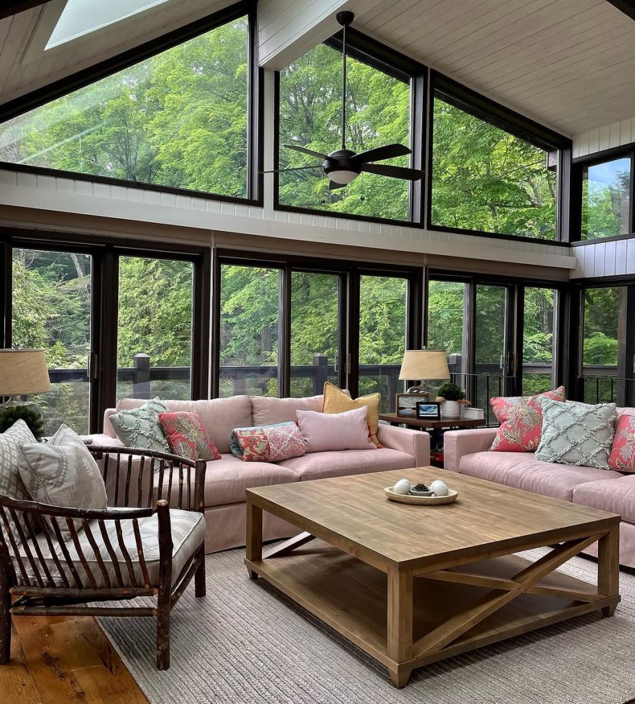 Pink sectional sofas with large windows overlooking green garden