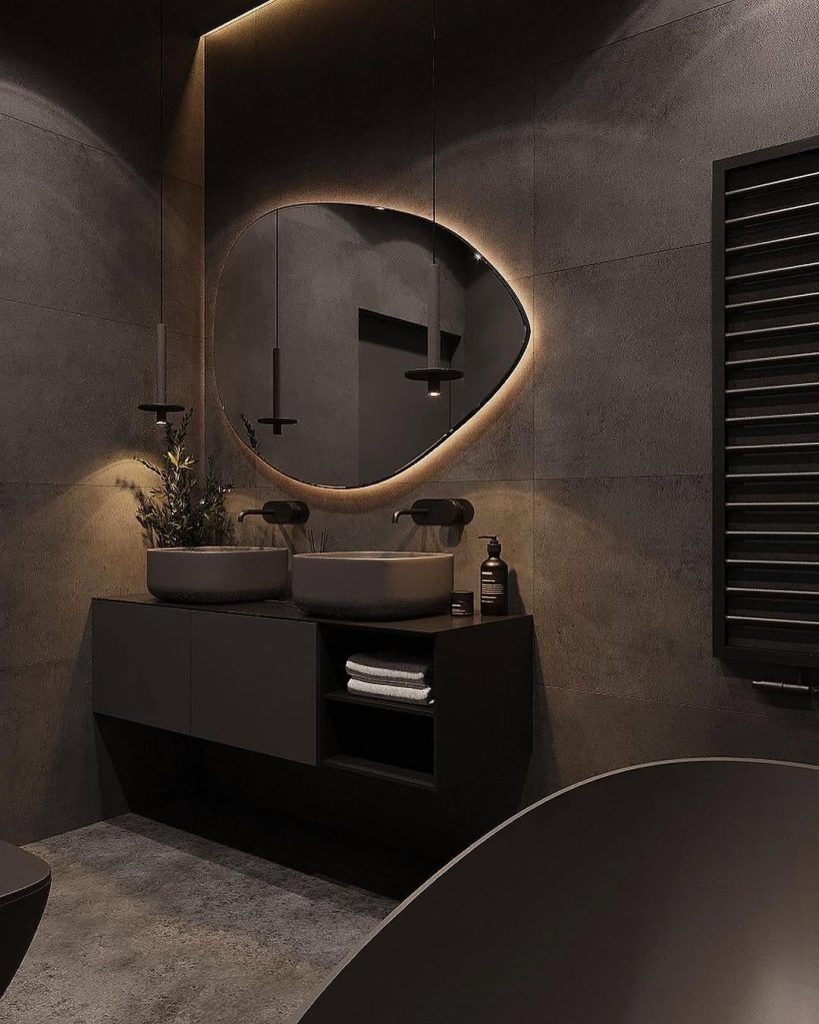 Modern dark bathroom with curved mirror and dual vessel sinks