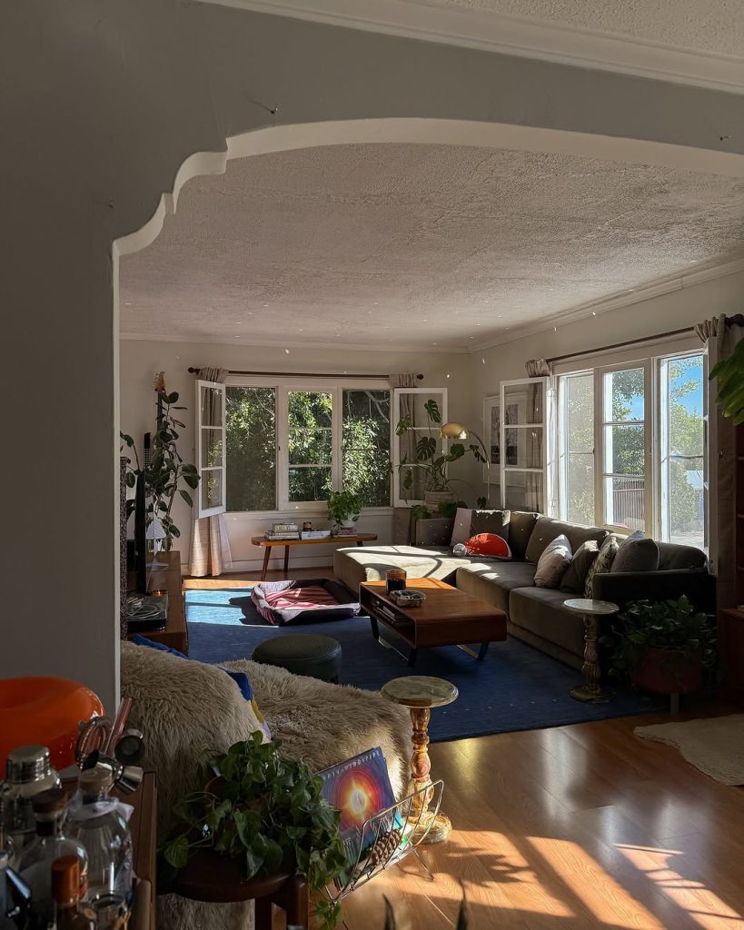 Bright living room with wraparound windows, sectional sofa, and plants