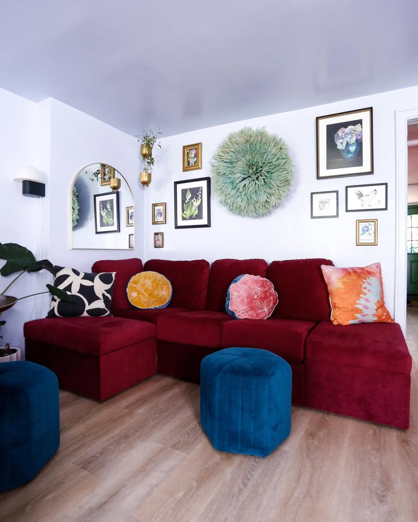 Colorful living room with burgundy sofa, gallery wall, and blue ottomans