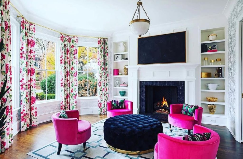 Living room with bright pink chairs and floral window treatments