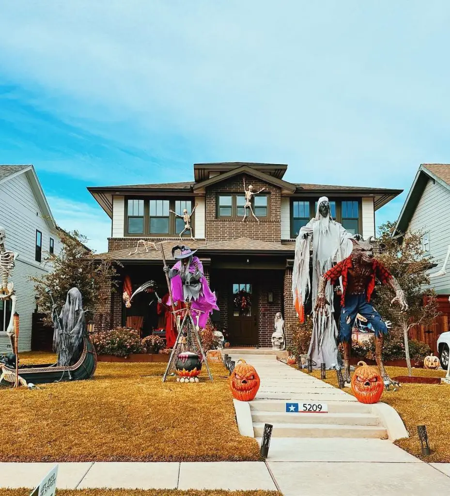 Front yard Halloween display with skeletons ghosts and carved pumpkins