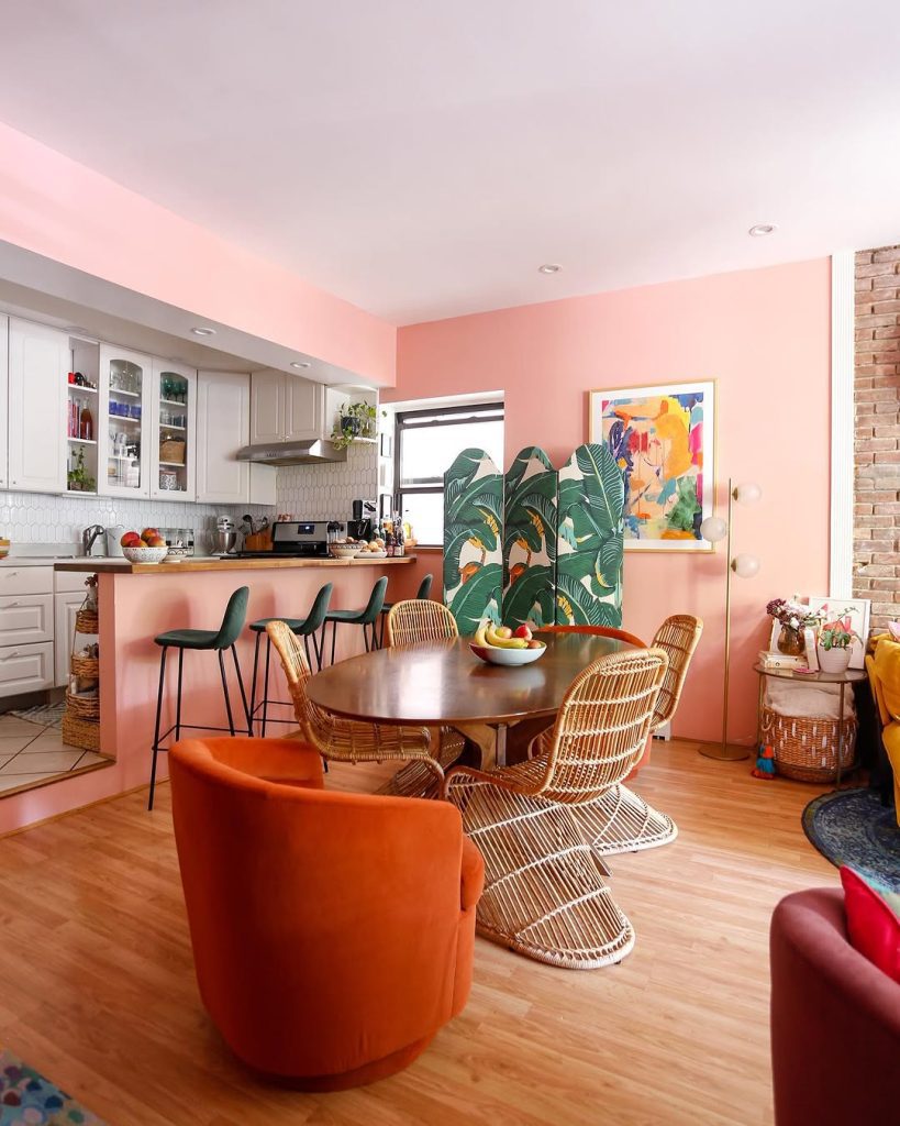 Bright dining room with coral walls and wicker chairs