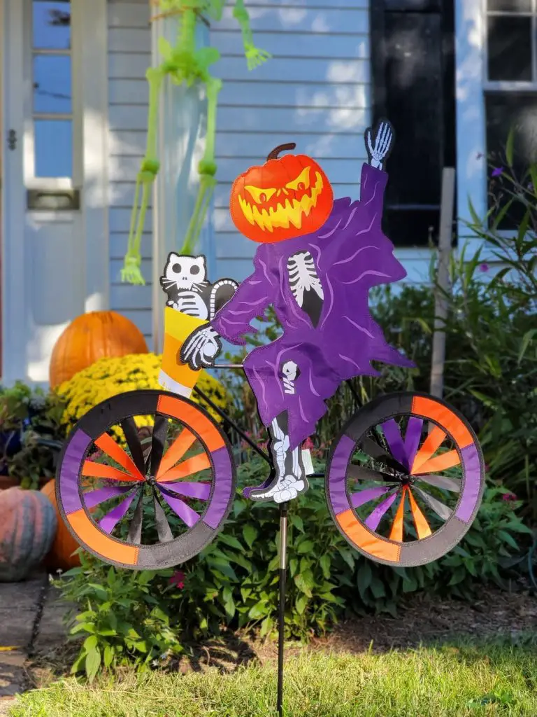 Skeleton riding bicycle with spinning wheels and Halloween decorations