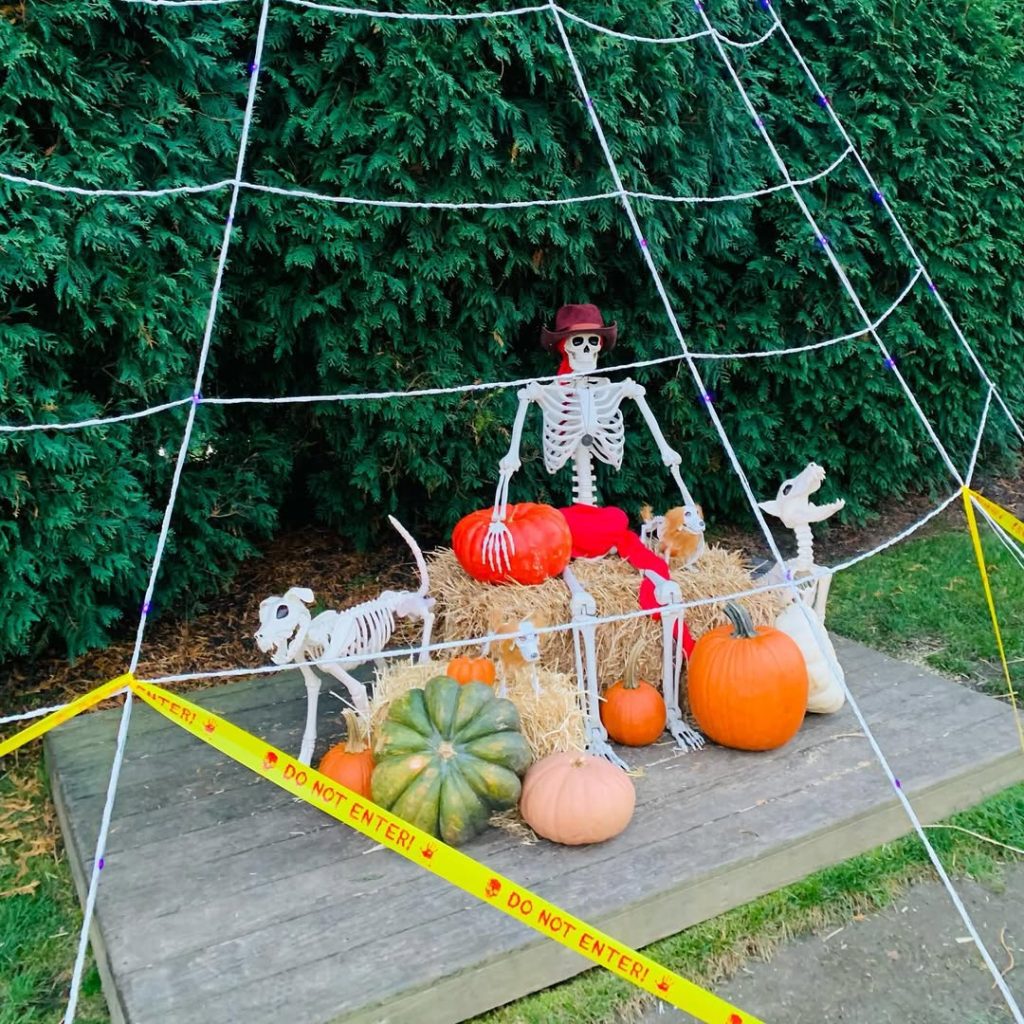 Halloween crime scene with skeleton investigators and caution tape