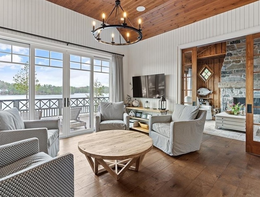 Gray armchairs around wooden table with large cottage windows