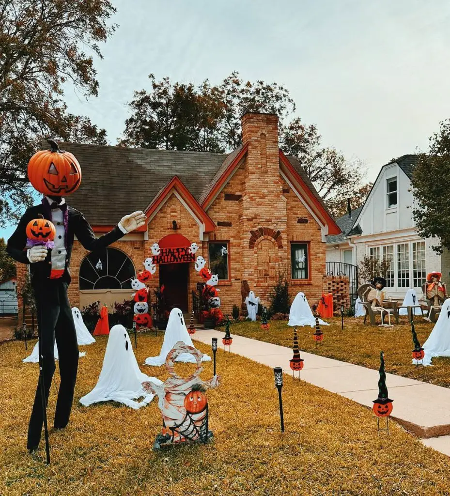 Front yard Halloween display with white ghosts and decorated brick house