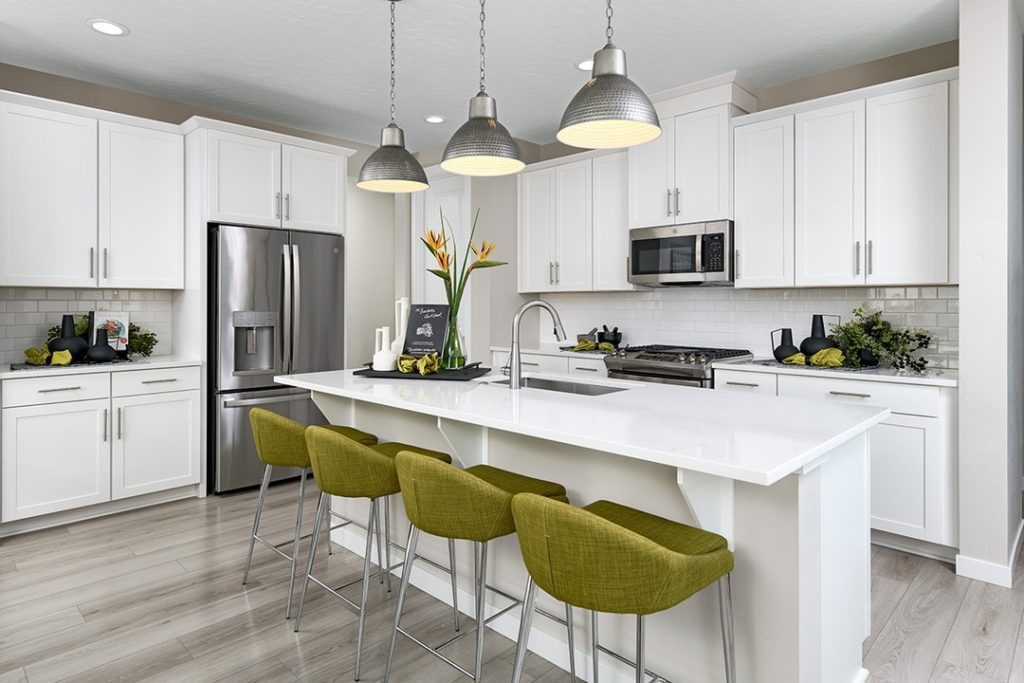 White kitchen with green bar stools, industrial pendant lights, subway tile backsplash