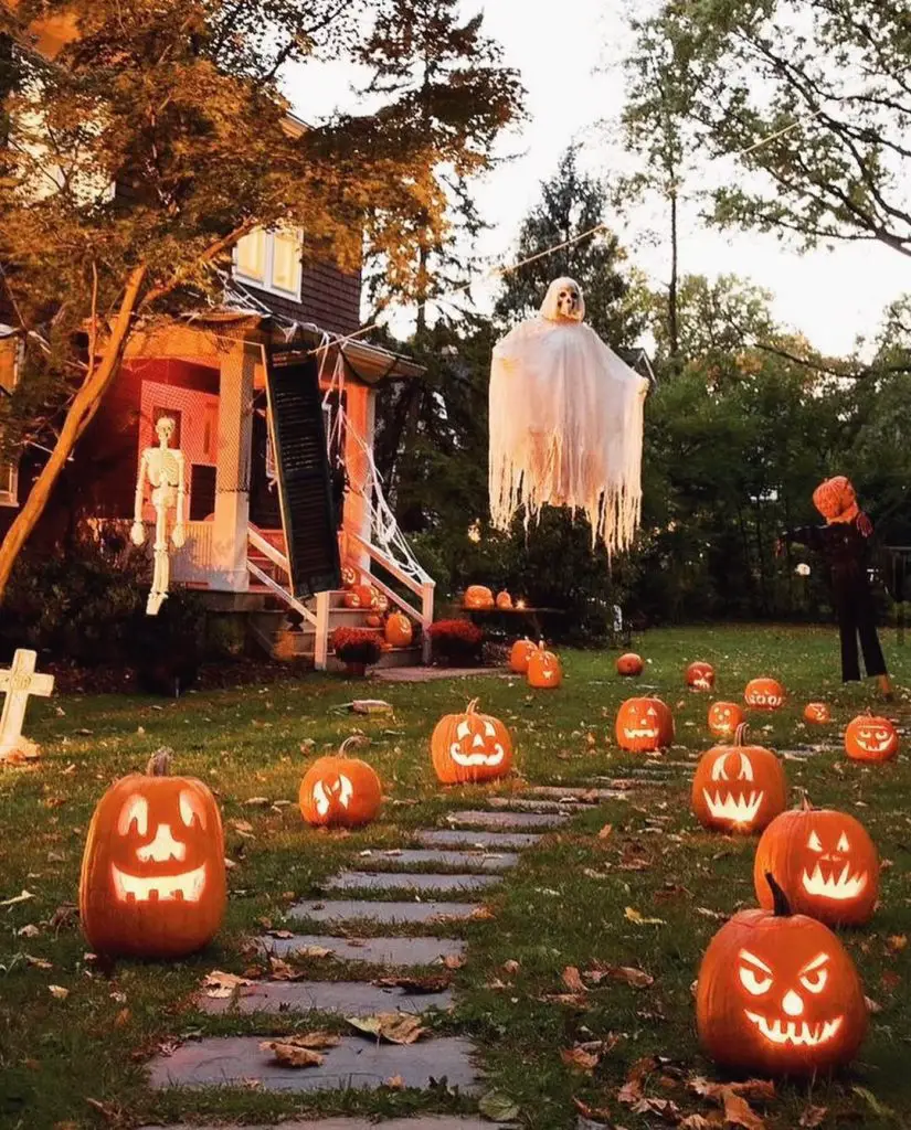 Glowing carved pumpkins lining walkway with hanging ghost overhead