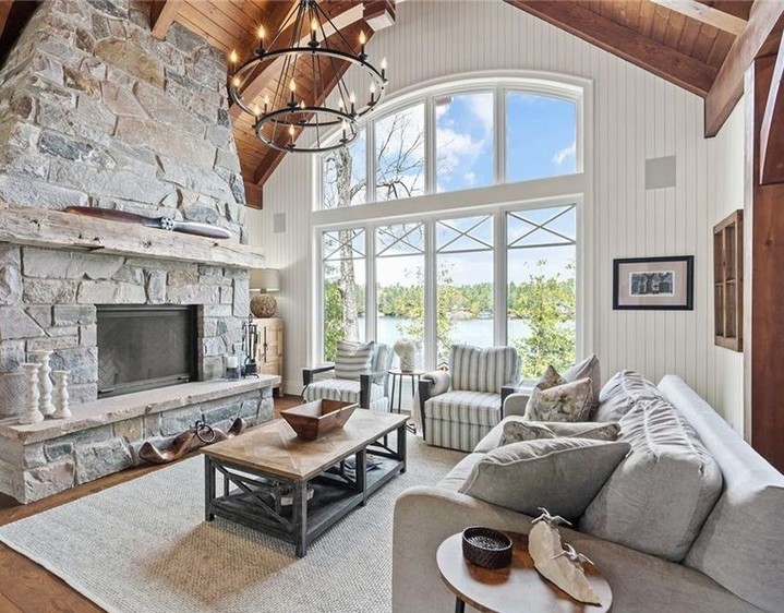 Living room with large stone fireplace arched windows beams