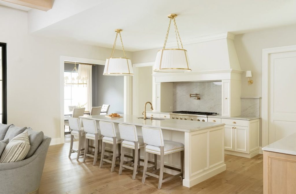 Classic white kitchen with marble counters and brass pendant lights