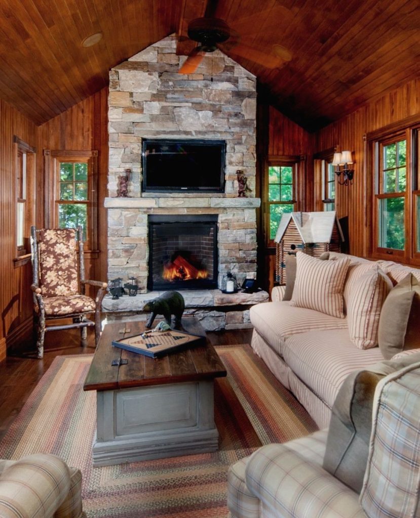 Wood paneled cabin living room stone fireplace plaid furniture
