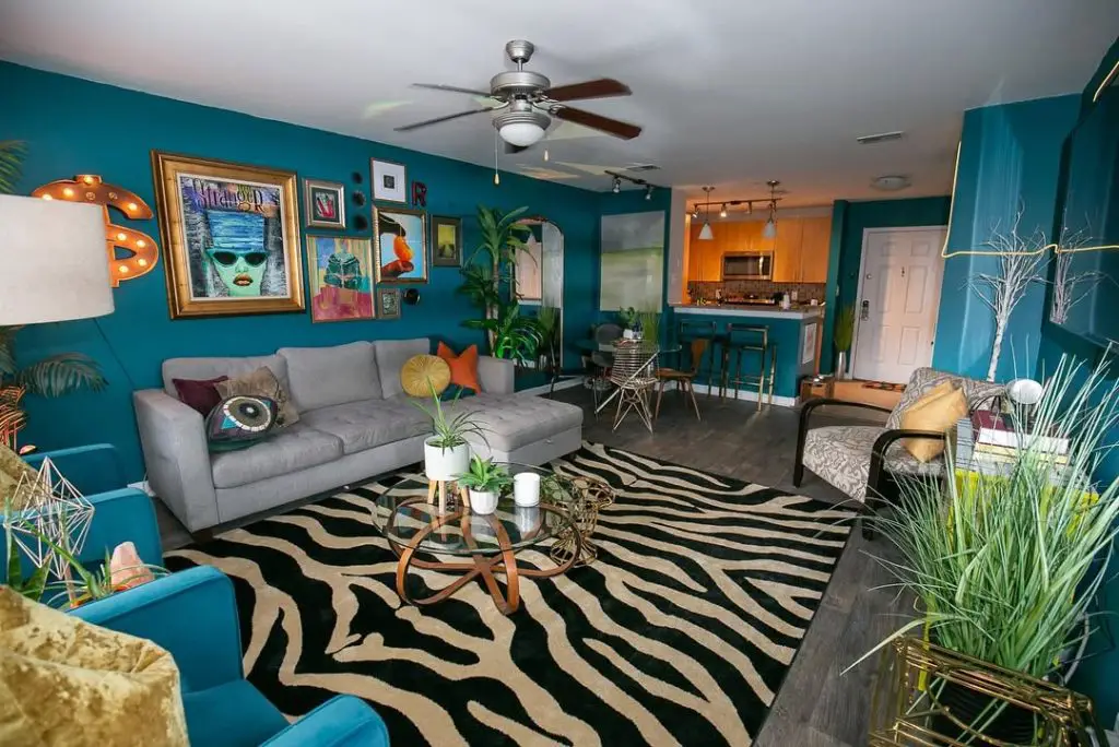 Teal walls with gray sectional, zebra rug, colorful eclectic artwork