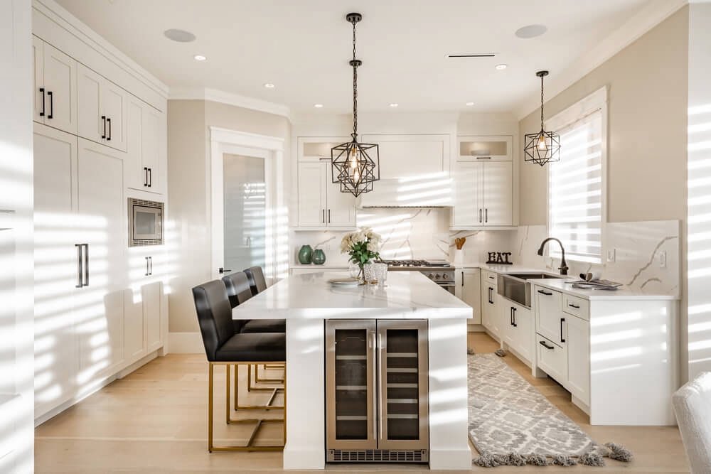 Luxury white kitchen with wine storage island, black leather stools, geometric pendant lights