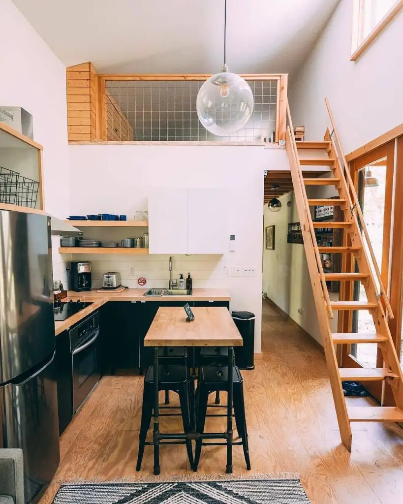 Loft kitchen with black cabinets, wood counters, island seating, stairs