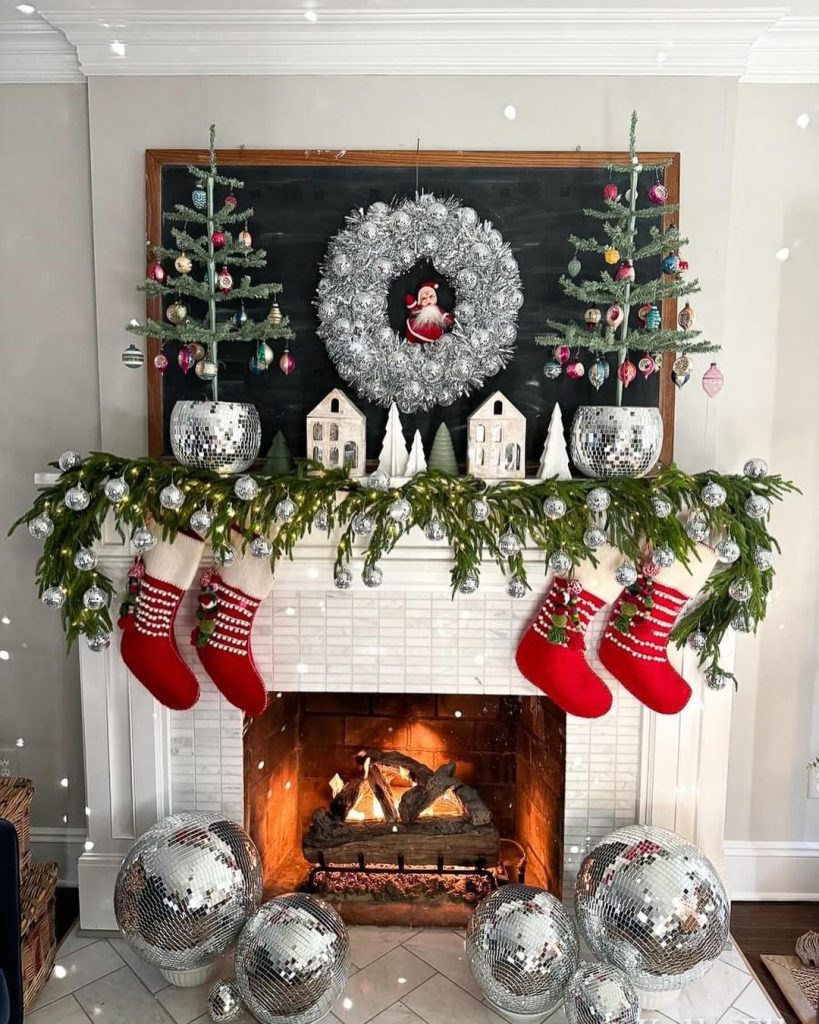 Fireplace mantel decorated with silver disco balls and Christmas garland