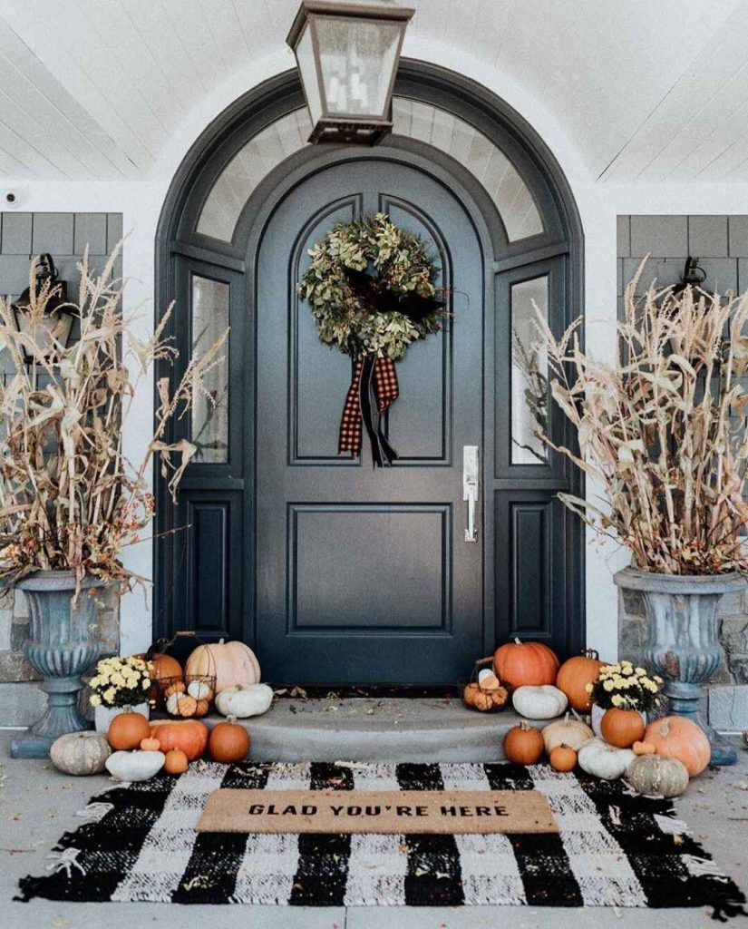Elegant front porch decorated with autumn pumpkins corn stalks and wreath
