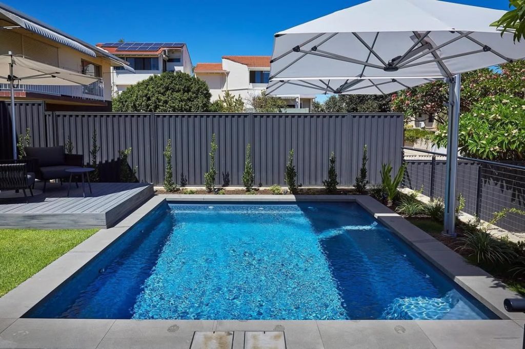 Suburban backyard pool with blue water and modern privacy fencing