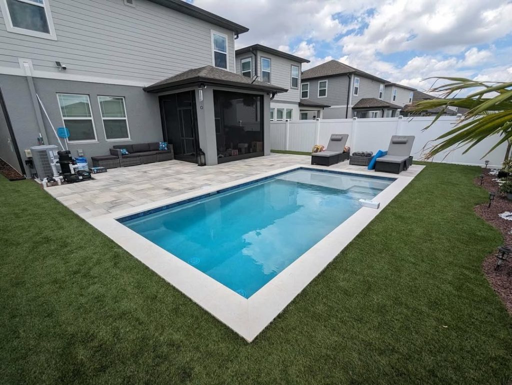 Rectangular backyard pool with patio and traditional home setting
