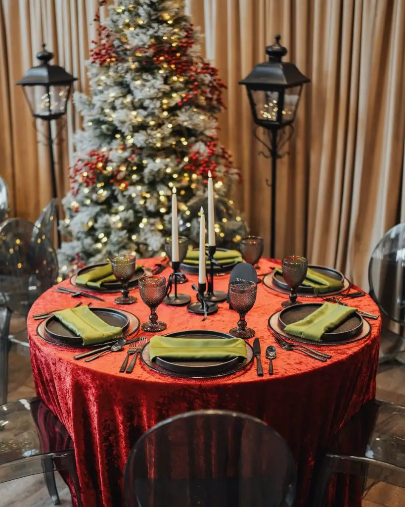 Round red velvet Christmas table with amber glasses dark plates