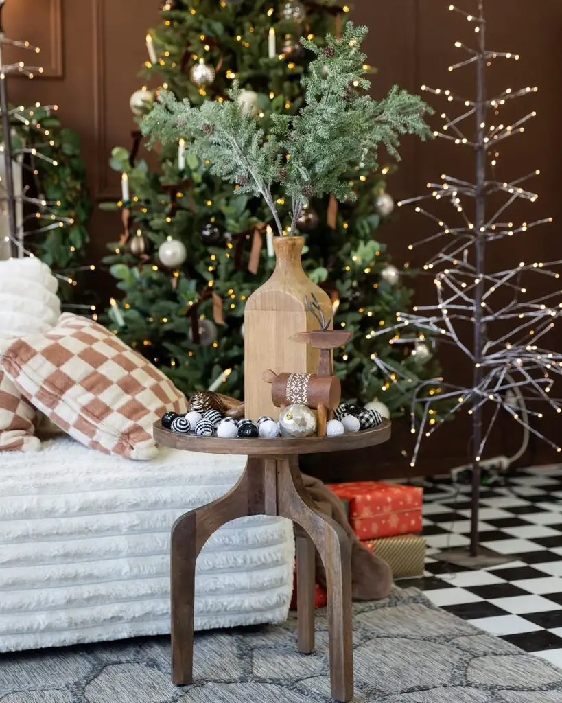 Christmas corner with white chair, evergreen branches, string lights, checkered pillows