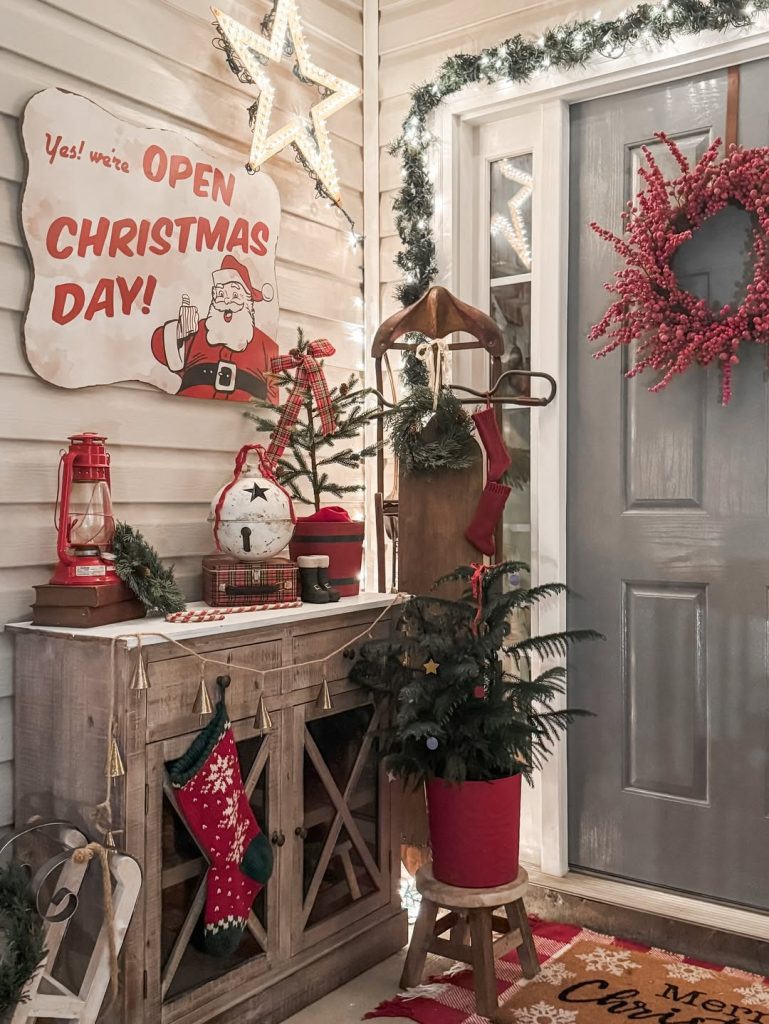 Farmhouse front porch decorated for Christmas with vintage signs and berry wreath