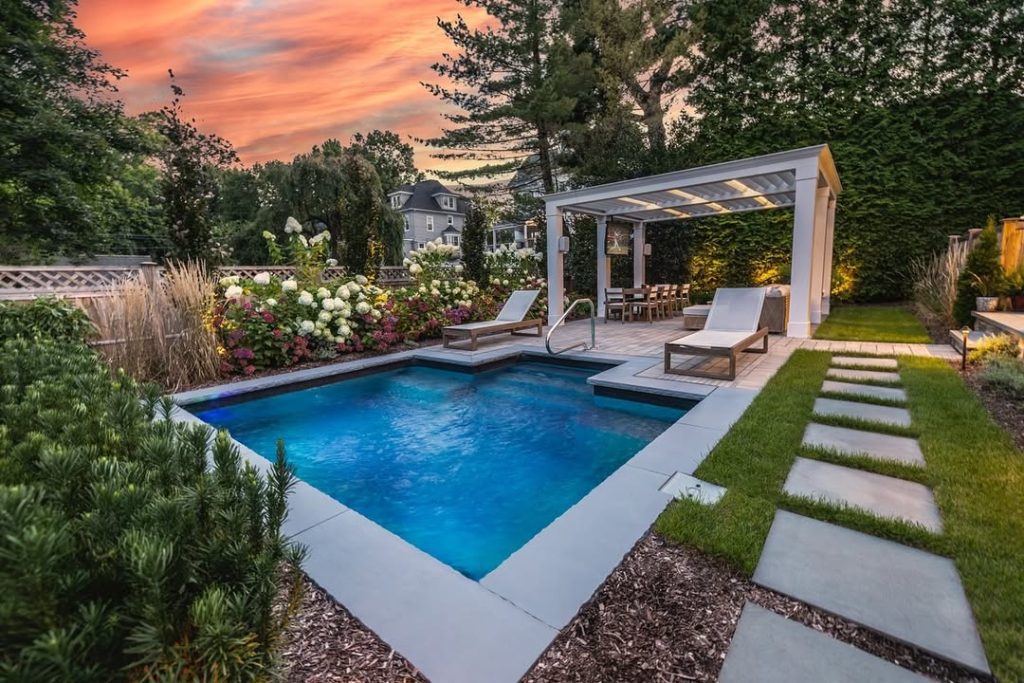 Pool with sunset lighting pergola and landscaped garden borders