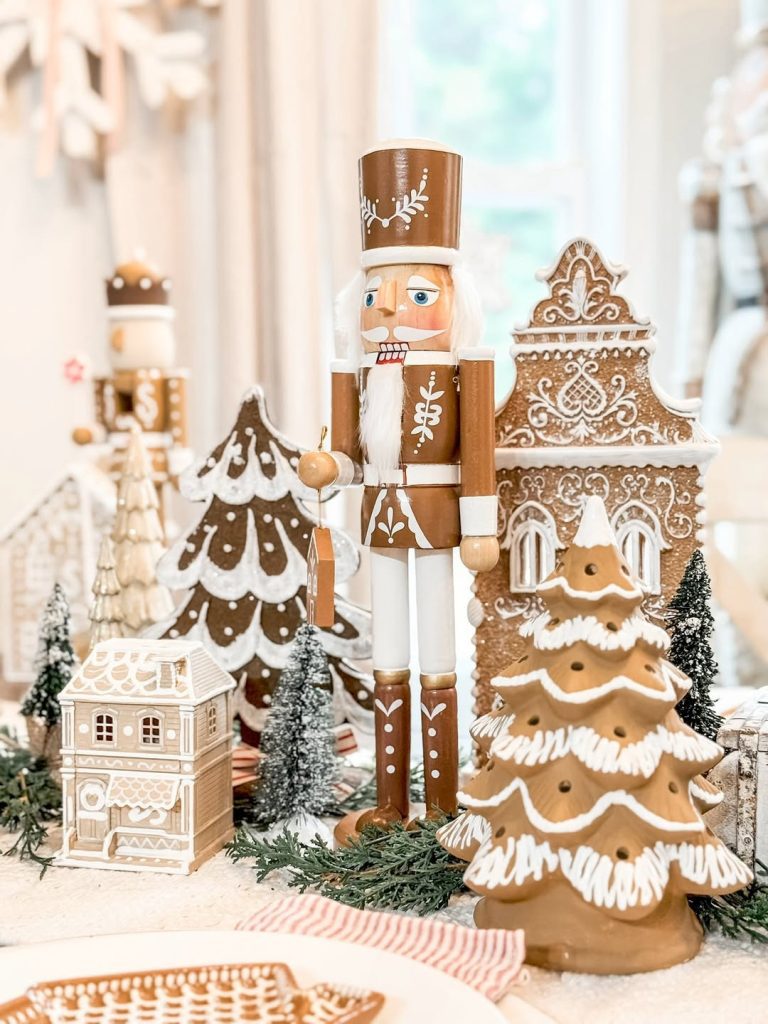 ingerbread village display with wooden nutcracker and miniature Christmas trees