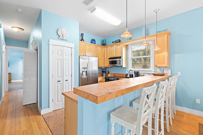 Light blue kitchen with wooden cabinets and breakfast bar seating