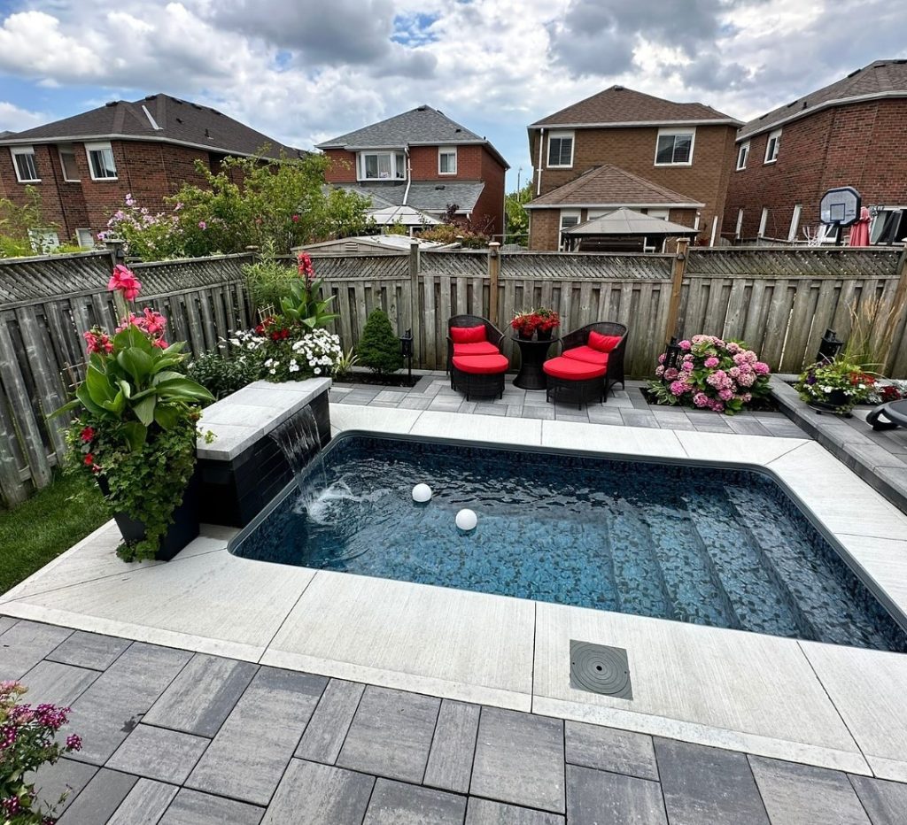 Rectangular backyard pool with stone deck and colorful garden furniture