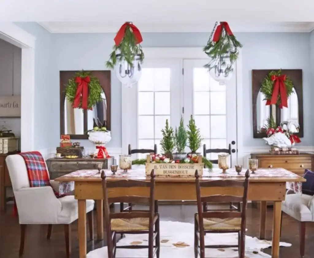 Rustic kitchen with Christmas wreaths, evergreen centerpieces, and farmhouse table