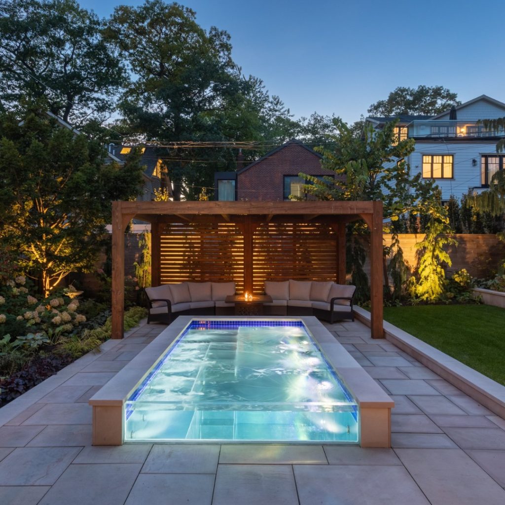 Illuminated rectangular pool with raised spa and wooden pergola