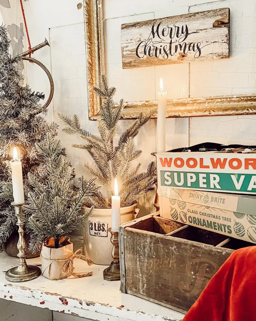 Farmhouse mantel with vintage signs, brass candlesticks, evergreen sprigs, weathered wood Christmas decor