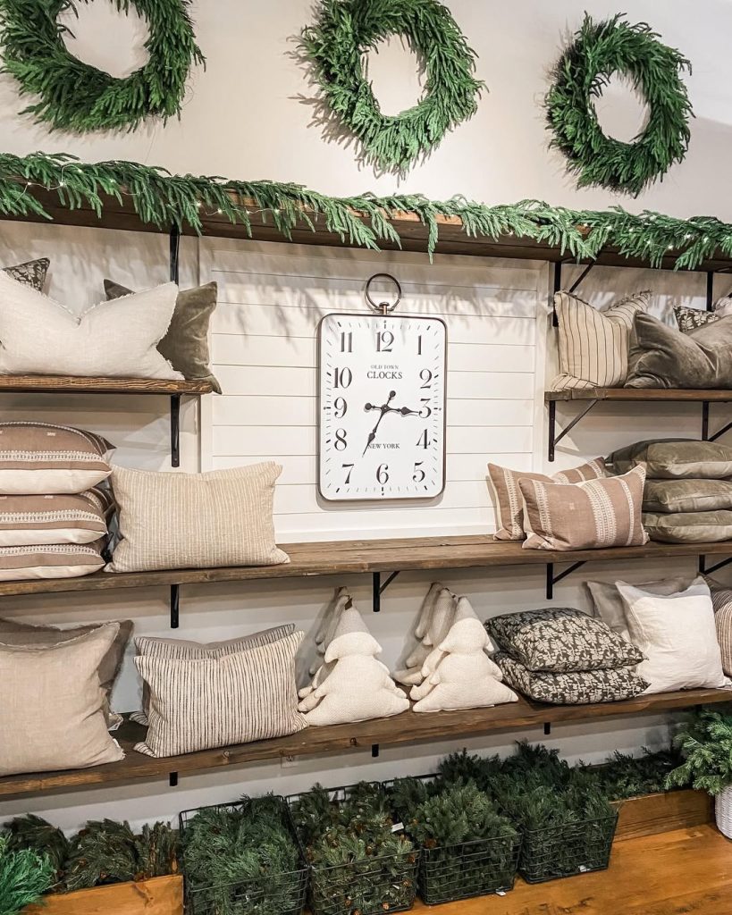 Shelving unit with Christmas wreaths pillows and clock