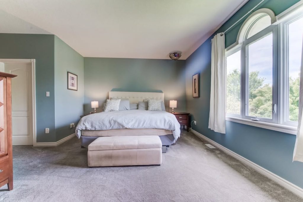 Spacious blue bedroom with elegant furniture and large windows