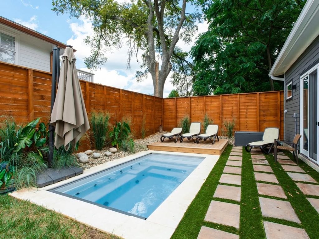 Modern rectangular pool with wooden deck and artificial grass landscaping
