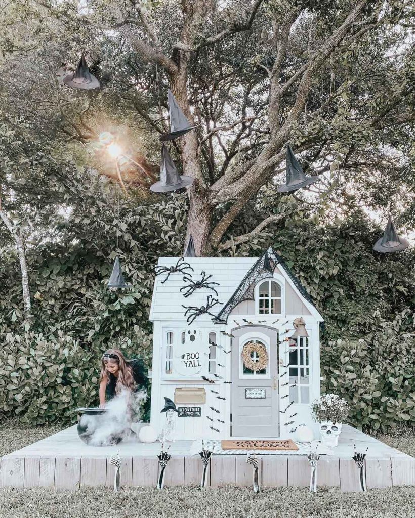 Outdoor Halloween playhouse display with witch hats skeleton hands fog effects