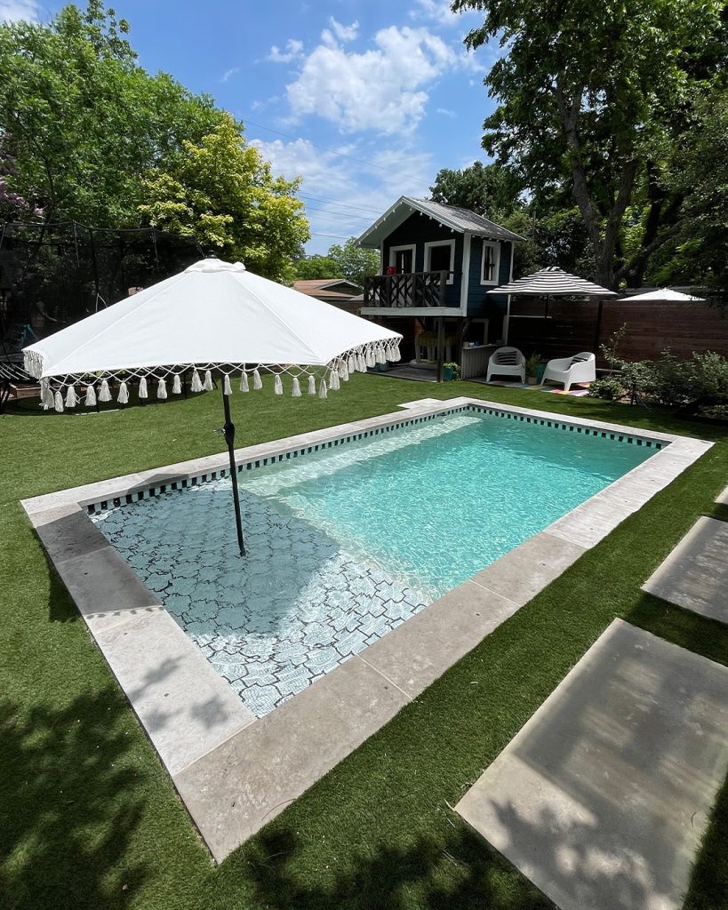 Rectangular family pool with treehouse and decorative umbrella shade