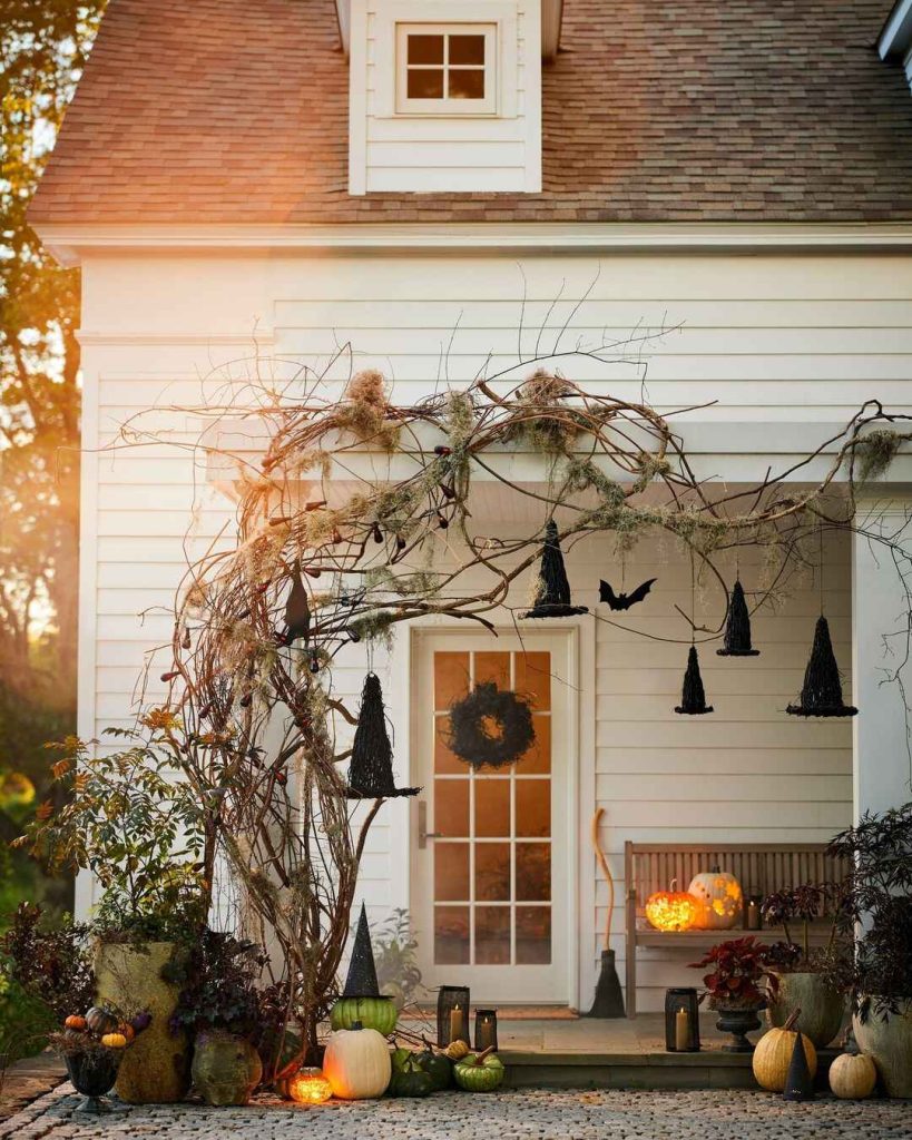 Front porch Halloween display with hanging witch hats twisted branches moss