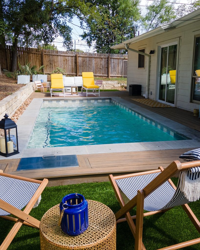 Traditional rectangular pool with colorful furniture and lawn surroundings