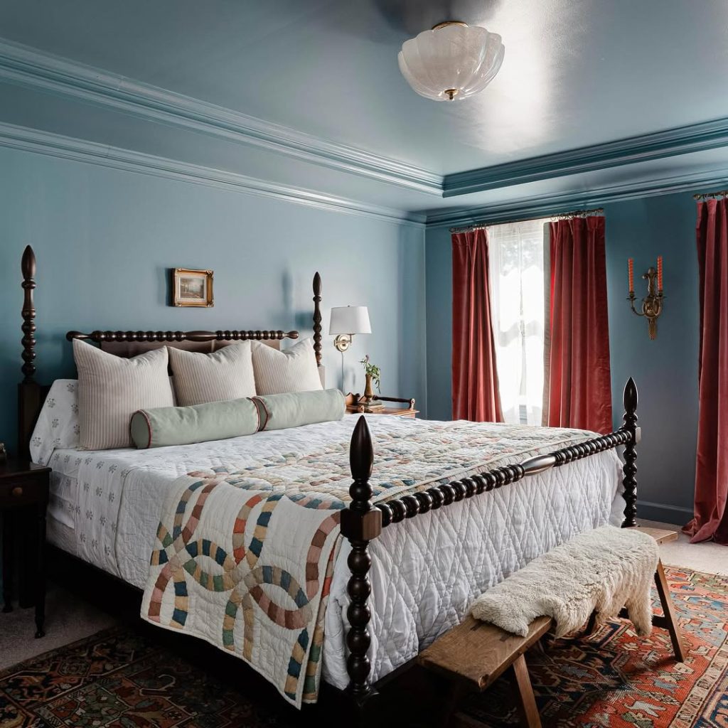 Traditional blue bedroom with four-poster bed and red curtains